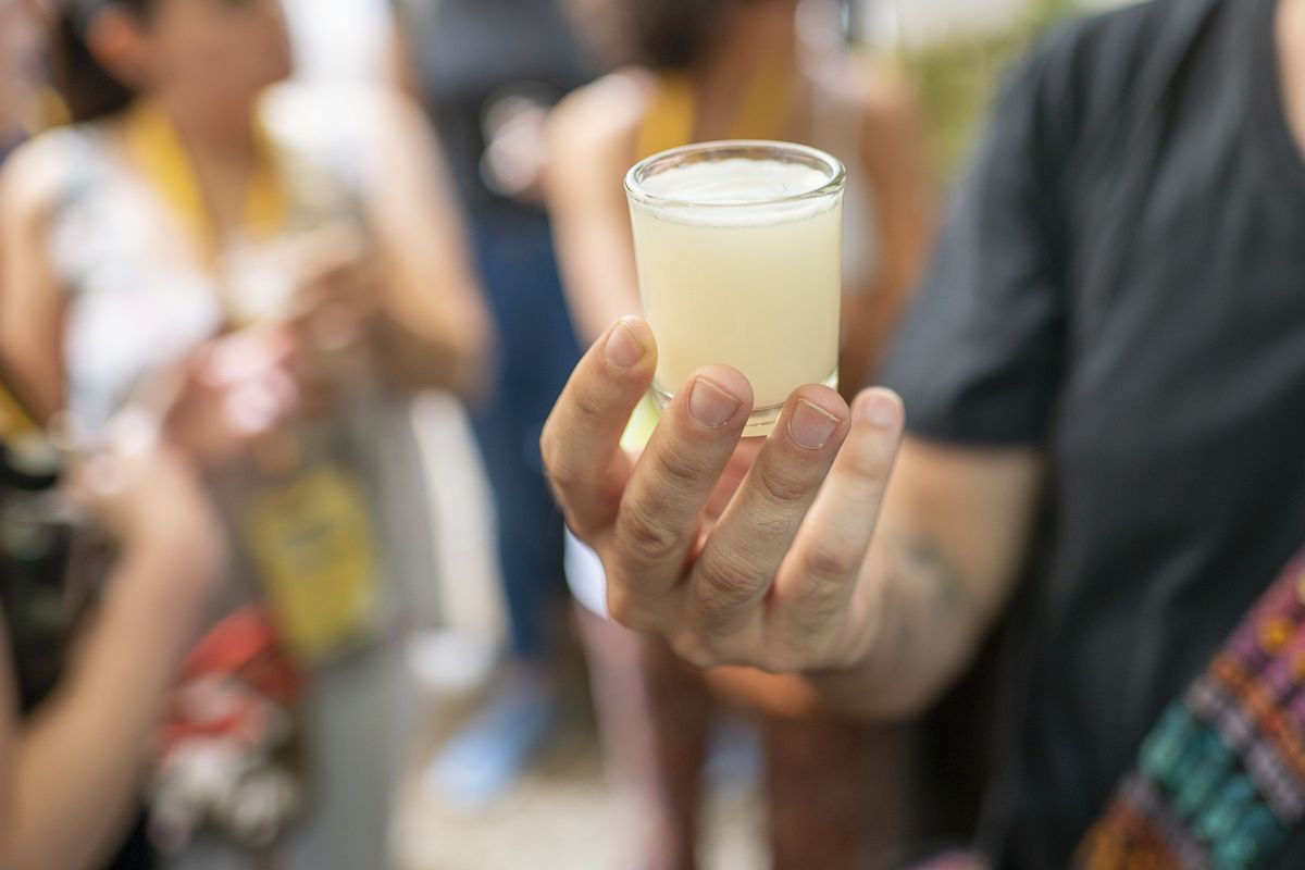 oaxaca, mexico iemand houdt een kopje van een traditionele drank pulque, ook bekend als octli, het is gemaakt van gefermenteerde agave en bevat een laag alcoholgehalte