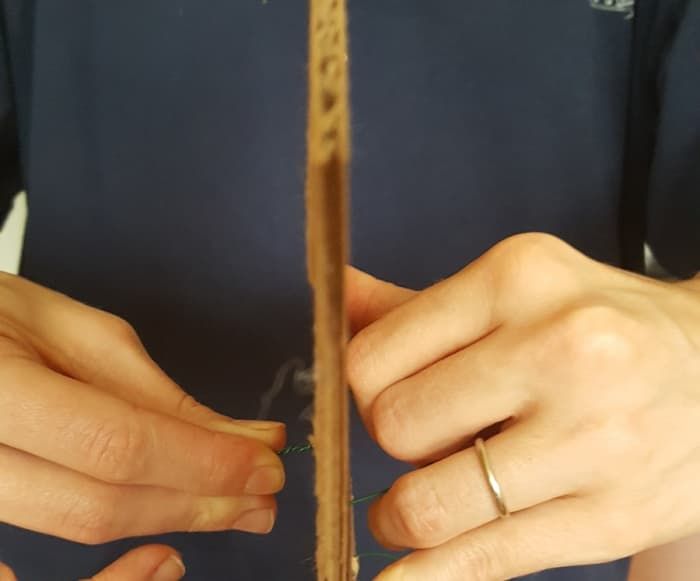 משוך את החוט דרך הקרטון כדי ליצור וו. סובב את קצוות החוט.