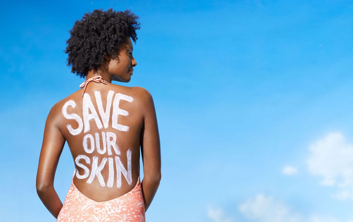 Schwarze Frau im Badeanzug mit Sonnencreme