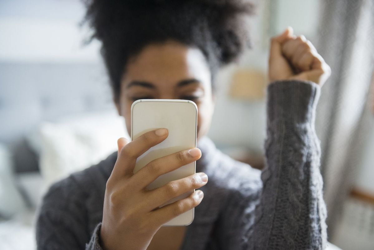 Afroameričanka praznuje med pošiljanjem sporočil na mobilni telefon
